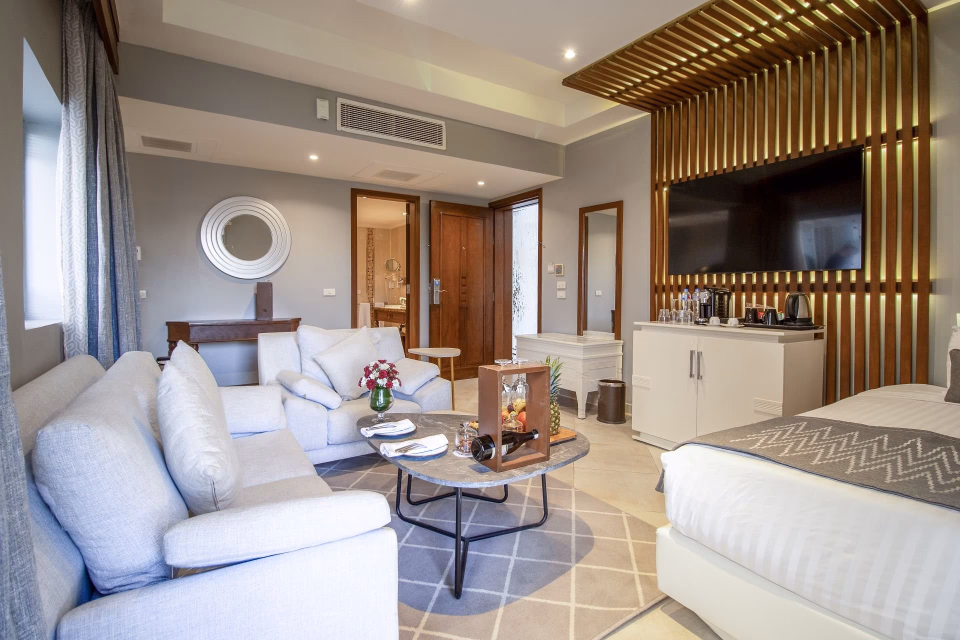 Junior Swim-Up Suite met witte bank, fauteuils en lamellenwand met tv, SUNRISE Crystal Bay Resort in Hurghada