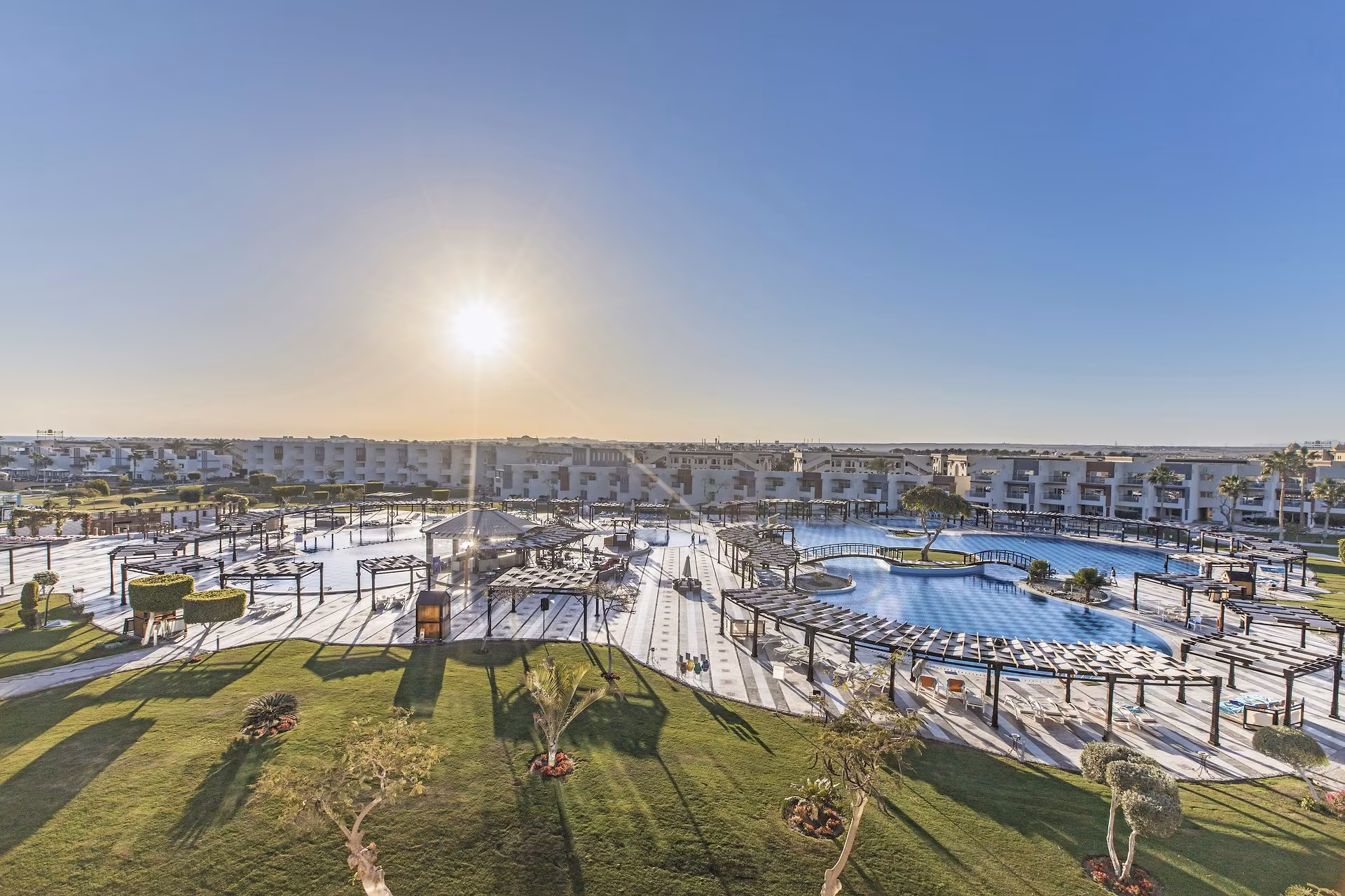 Luchtfoto bij zonsopkomst over de zwembaden, tuinen en gebouwen, SUNRISE Crystal Bay Resort in Hurghada