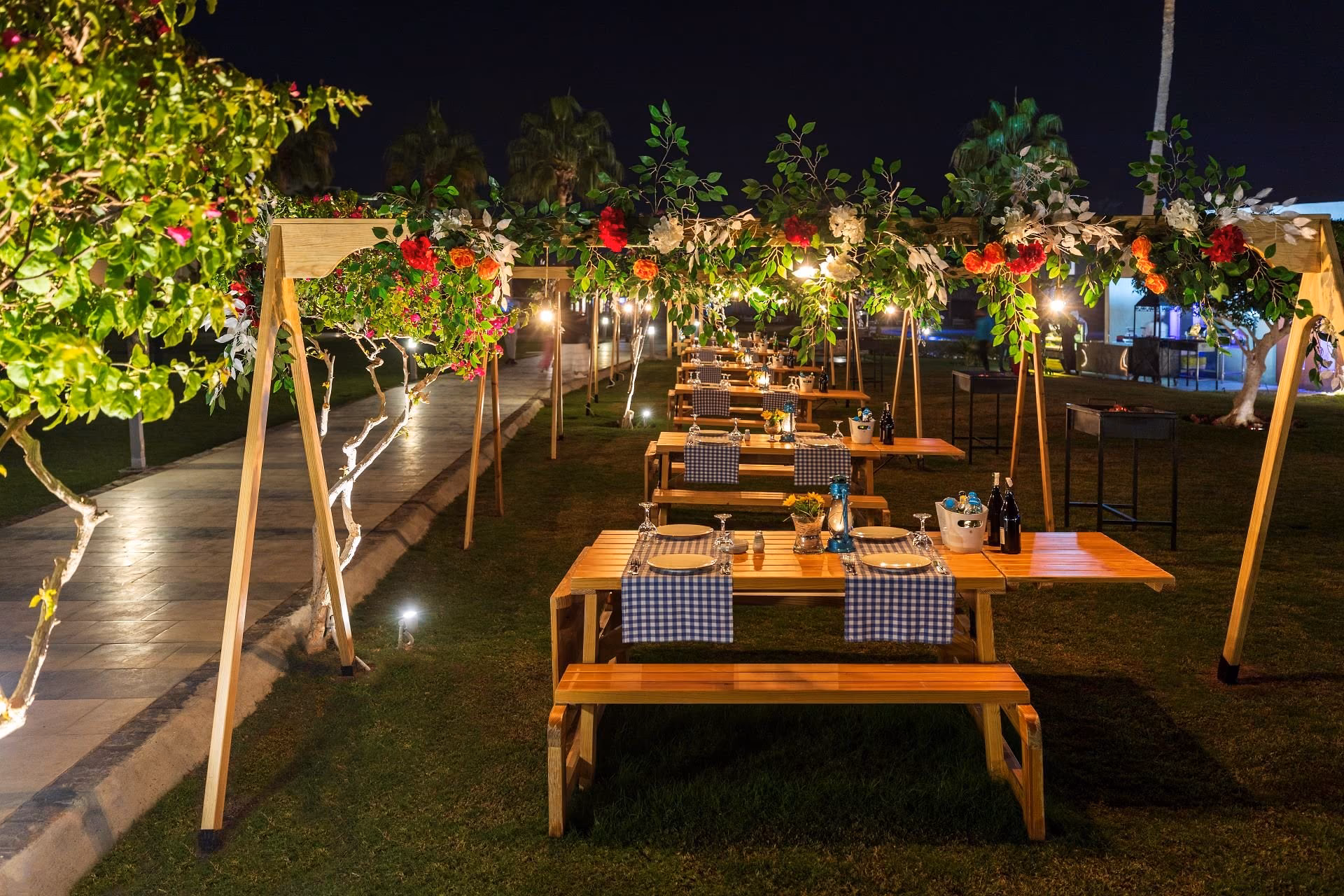 Houten picknicktafels onder verlichte bloembogen in de tuin bij restaurant Mangal, SUNRISE Crystal Bay Resort in Hurghada