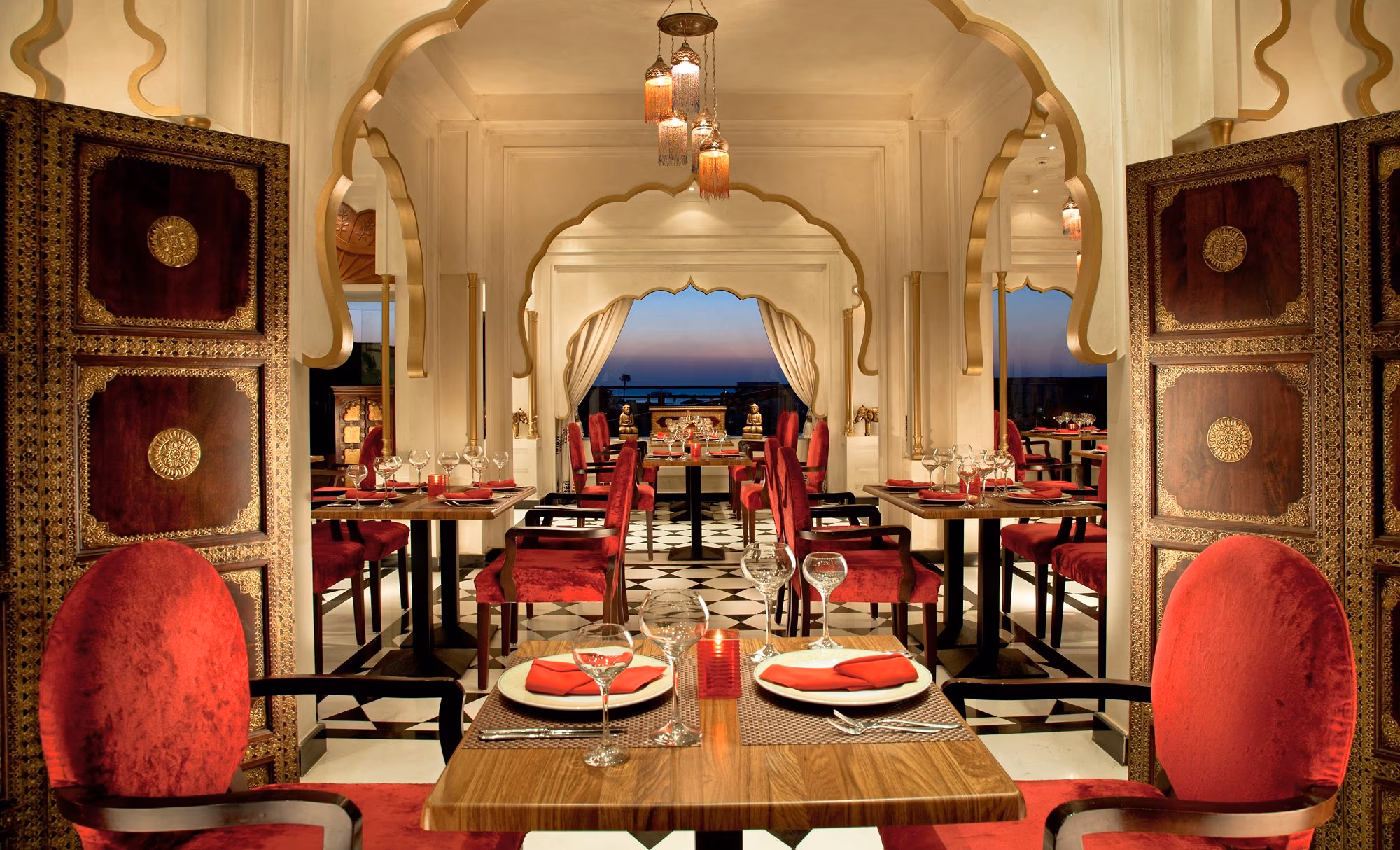 Gedekte tafel met rode stoelen tussen bewerkte houten panelen in Manohar, zee op de achtergrond, SUNRISE Crystal Bay Resort in Hurghada