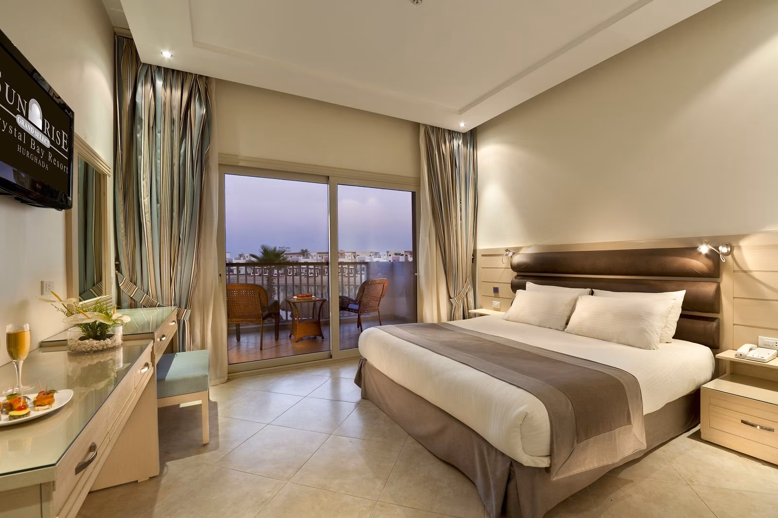 Slaapkamer met tweepersoonsbed en balkon met zicht op zee in de schemering, SUNRISE Crystal Bay Resort in Hurghada