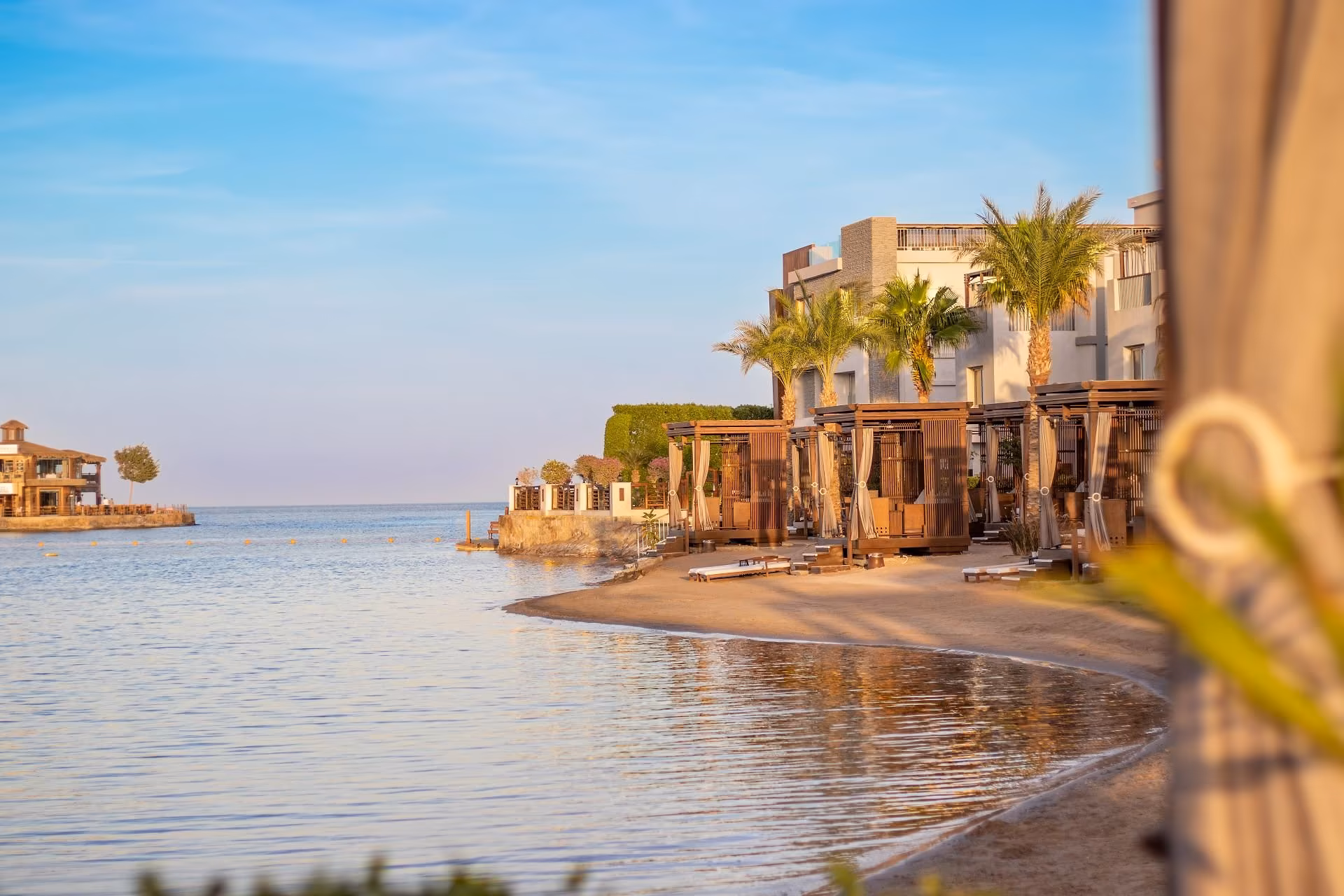 Strand aan de lagune met cabana's en de gebouwen erachter, SUNRISE Crystal Bay Resort in Hurghada