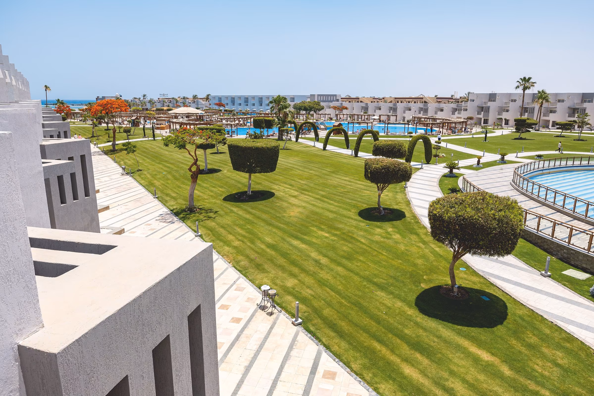 Gazons met gesnoeide bomen tussen de laagbouw en de zwembaden, SUNRISE Crystal Bay Resort in Hurghada