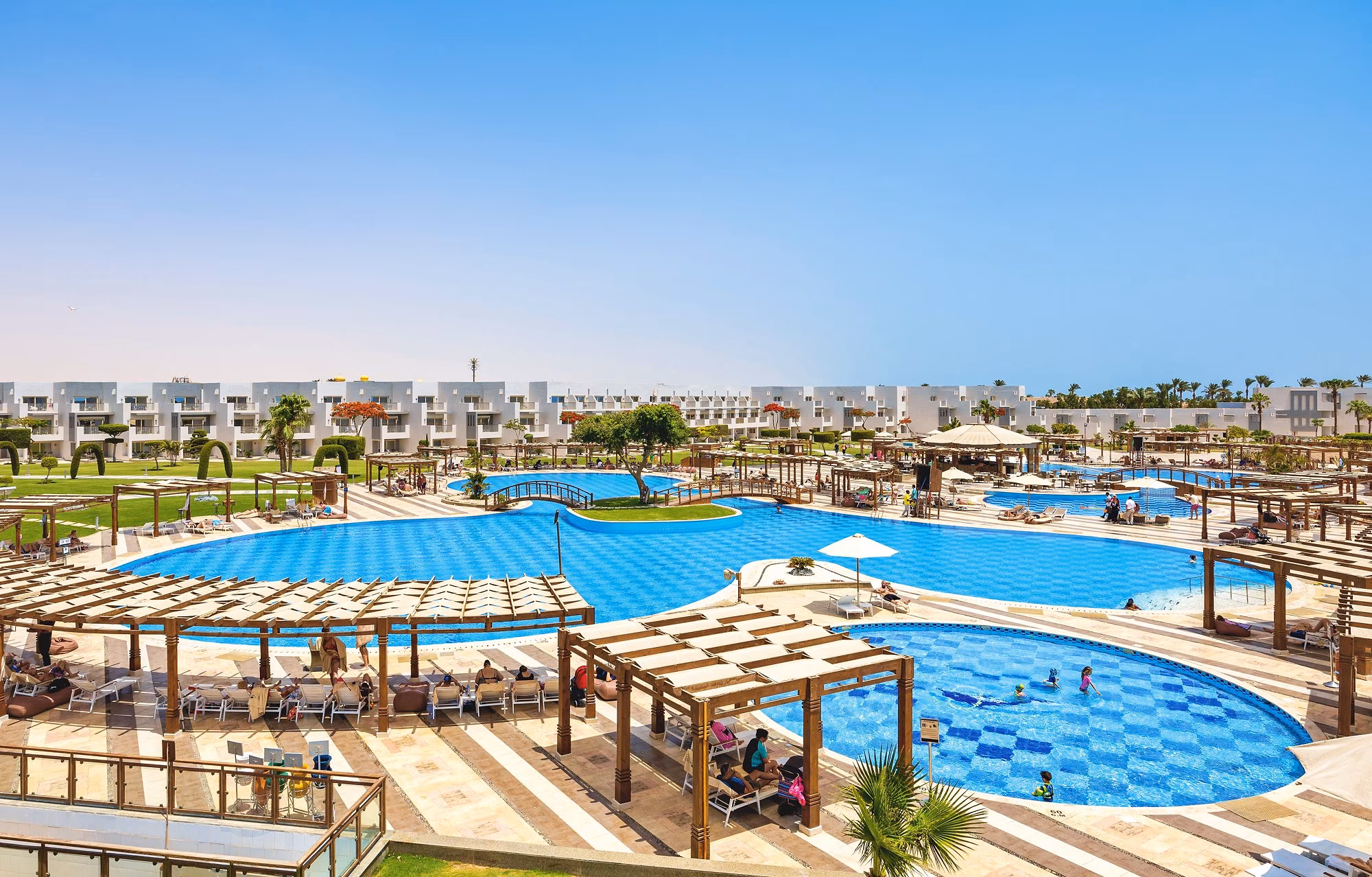Grote zwembaden met geblokte bodem, eilandje en pergola's, kamers op de achtergrond, SUNRISE Crystal Bay Resort in Hurghada