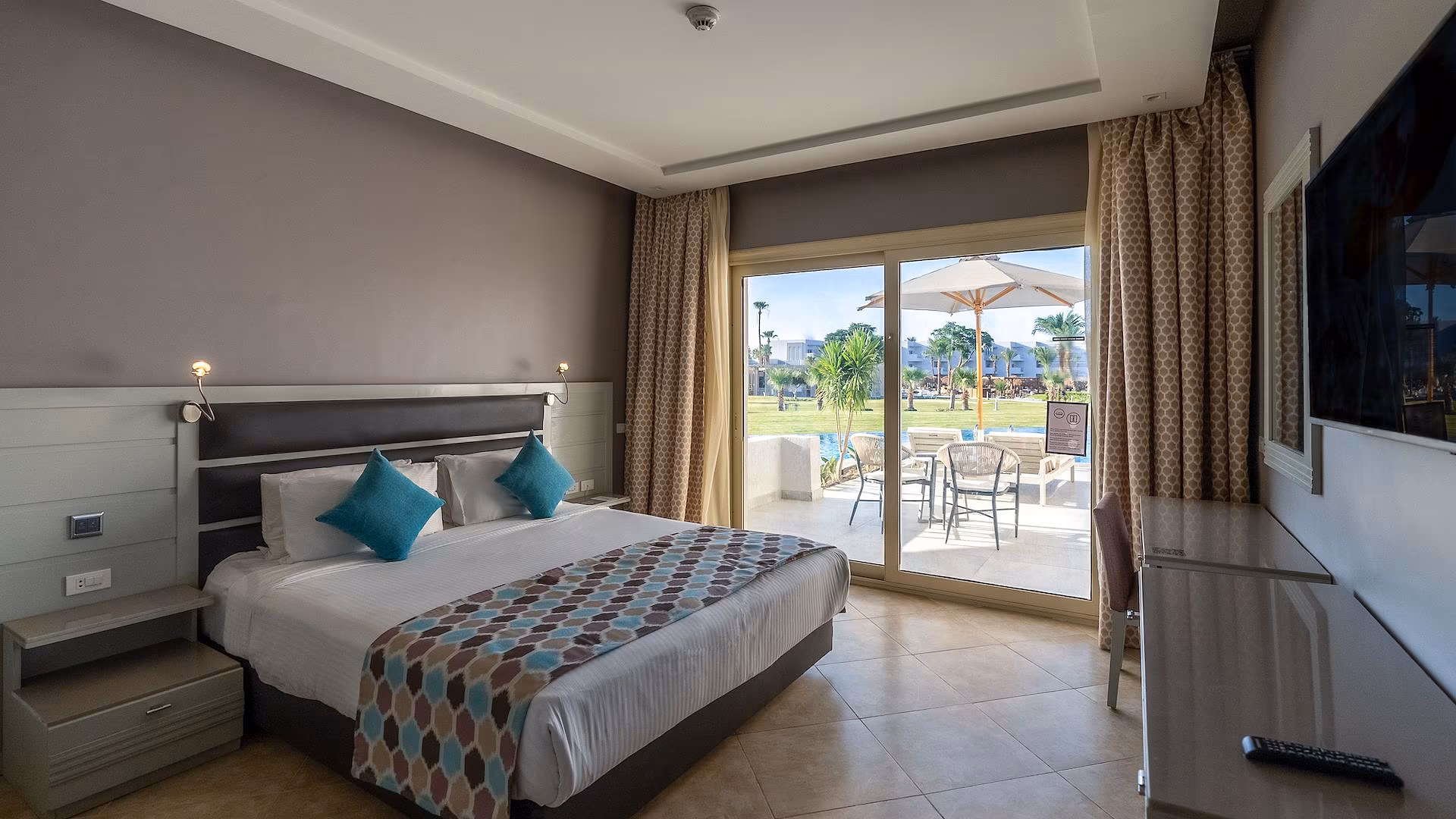 Kamer met kingsize bed en schuifpui naar een terras met parasol, SUNRISE Crystal Bay Resort in Hurghada